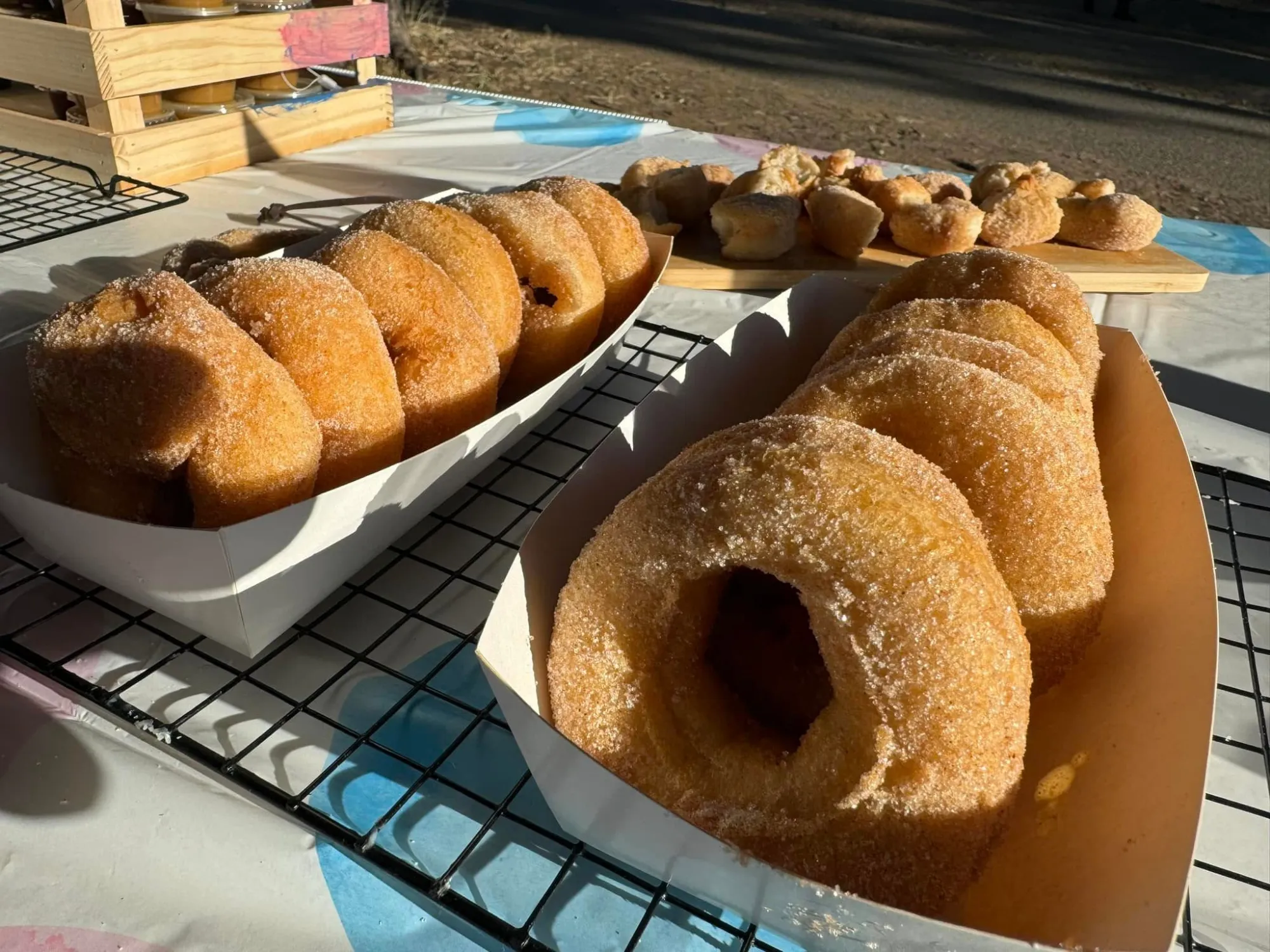 Trays of gluten free cinnamon sugar doughnuts on a cooling rack in the afternoon sun